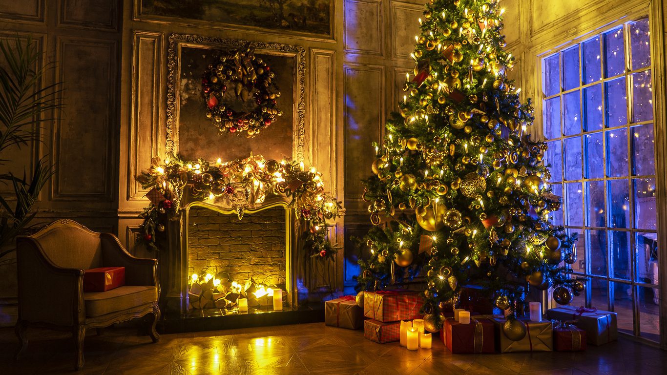 Christmas and New Year interior decoration. Green tree decorated with toys, gifts, present boxes, flashing garland, illuminated lamps. Fireplace and xmas tree. Cozy Christmas atmosphere