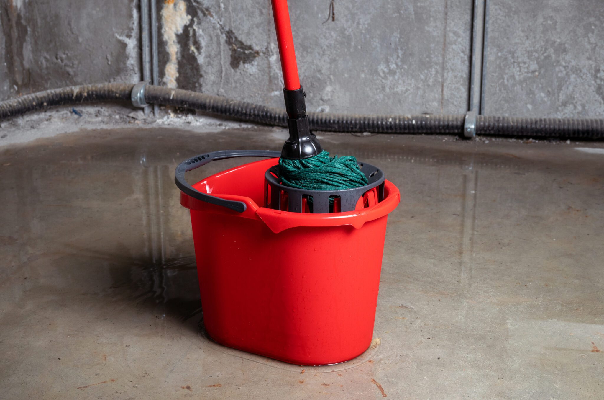 Cleaning up lots of water on floor from multiple leaks in wall and ceiling. Water damage from rain, snowmelt or pipe burst. Selective focus.